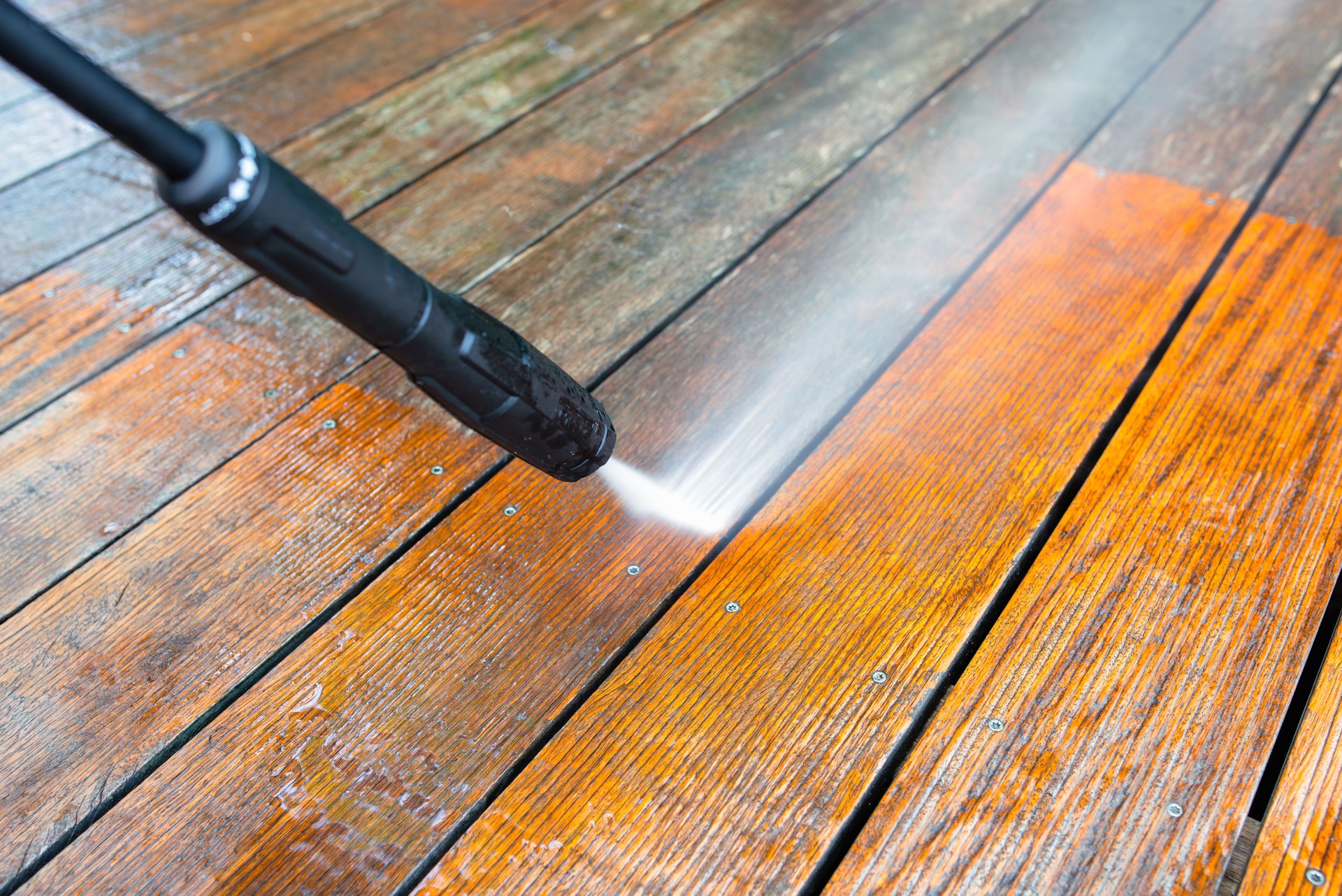 cleaning the terrace with a pressure washer - high-pressure cleaner on the wooden surface of the terrace - very shallow depth of field - sharpness on the terrace board under a stream of water