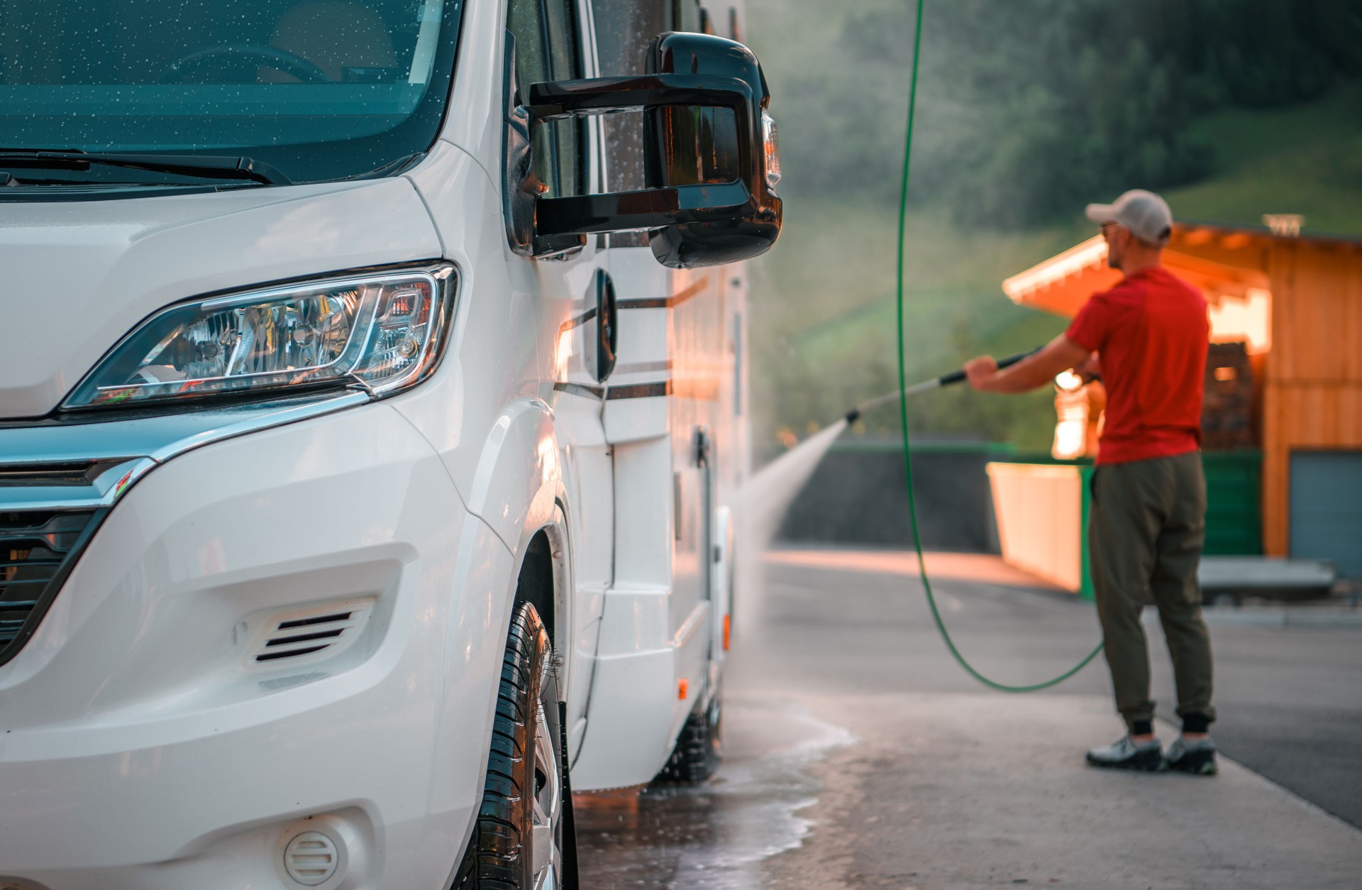 Man Washing a White Camper Van at a Service Station in the Morning Light